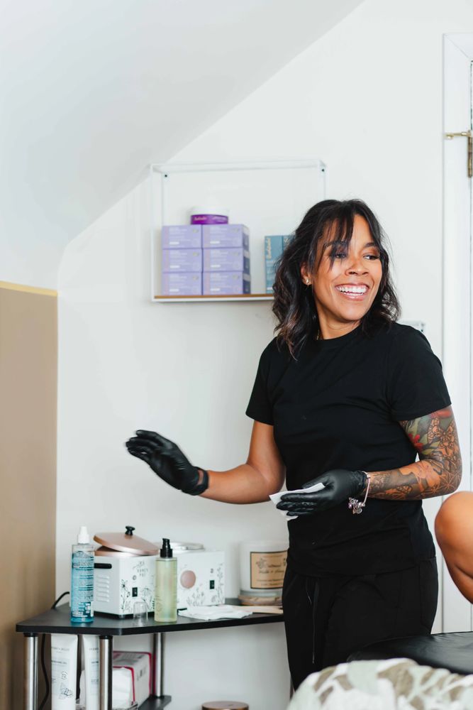 Thiara, the licensed nail technician and esthetician at TLC Nails and Esthetics, smiling in gloves beside her supply cart in the private one-client suite in Nottingham, MD