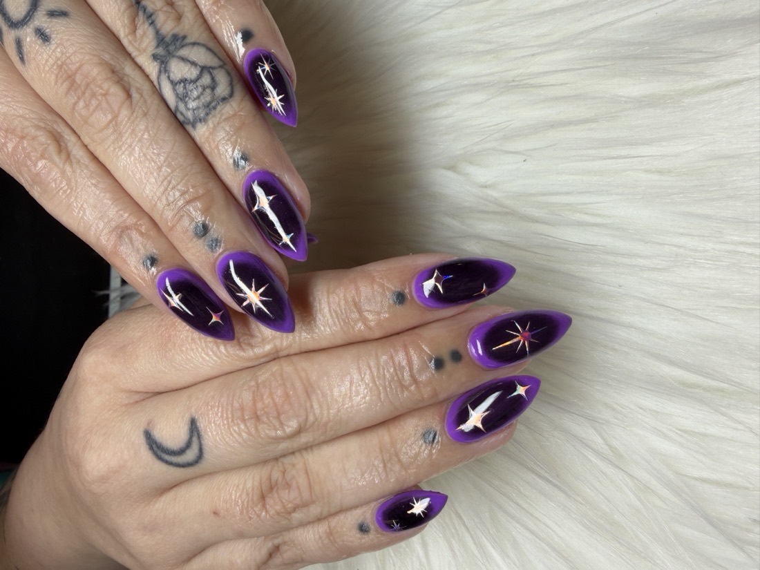 Long almond Hard Gel nails in a deep purple gloss with holographic star accents by TLC Nails and Esthetics in Nottingham, MD
