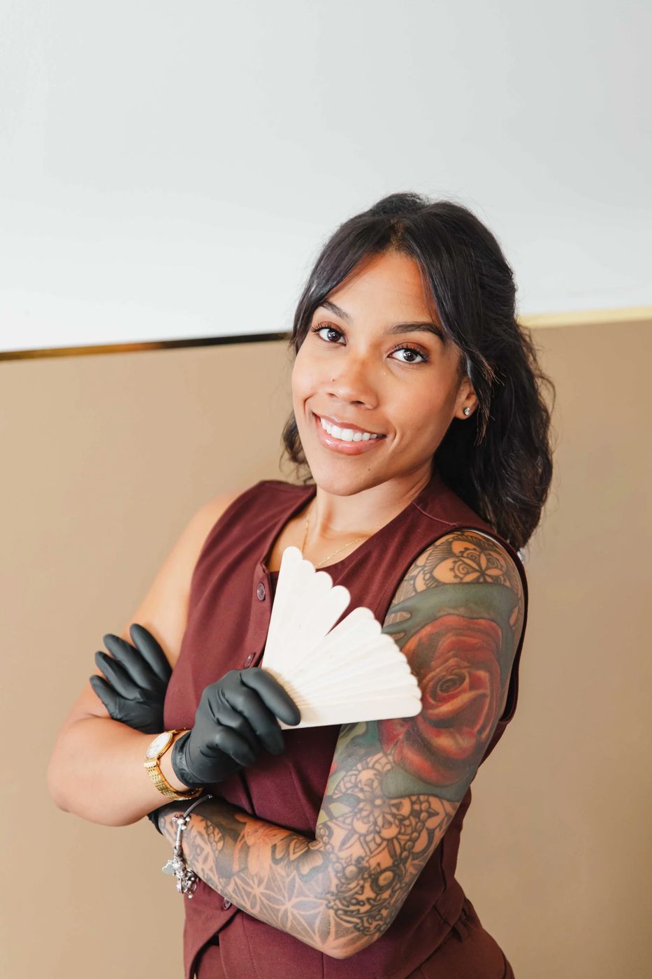 Thiara, the licensed esthetician at TLC Nails and Esthetics in Nottingham, MD, holding a fan of wooden wax applicators in black gloves before a Brazilian wax appointment