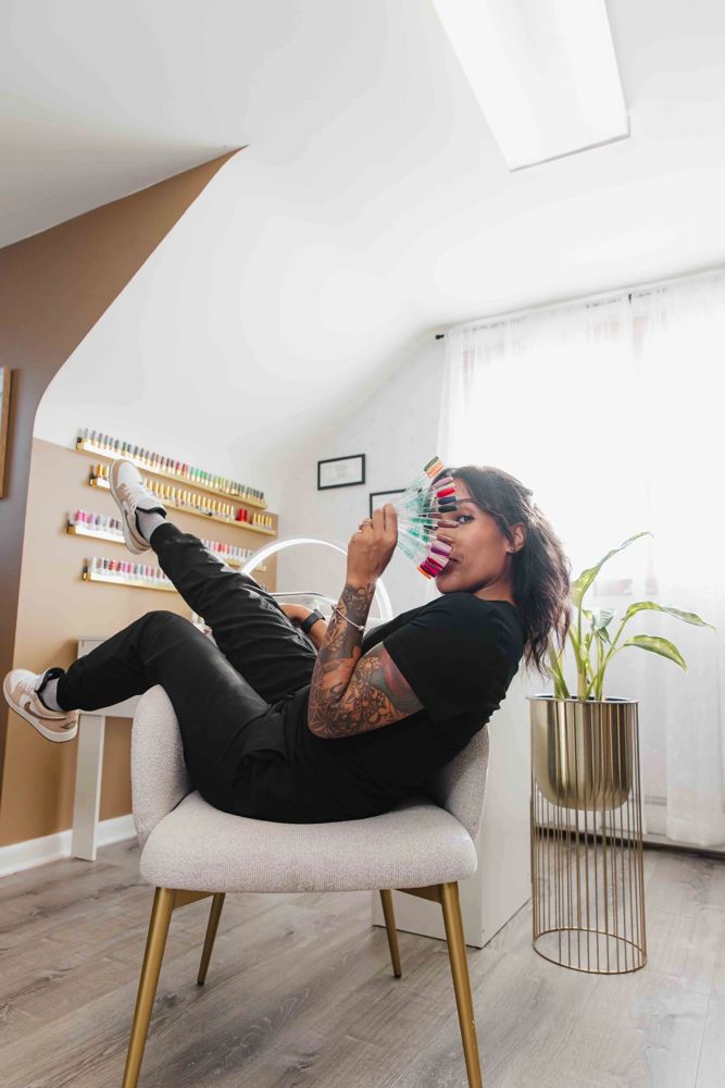 Thiara, licensed nail technician and esthetician, holding a fan of gel polish colors in her private one-client suite at TLC Nails and Esthetics on Belair Rd in Nottingham, MD